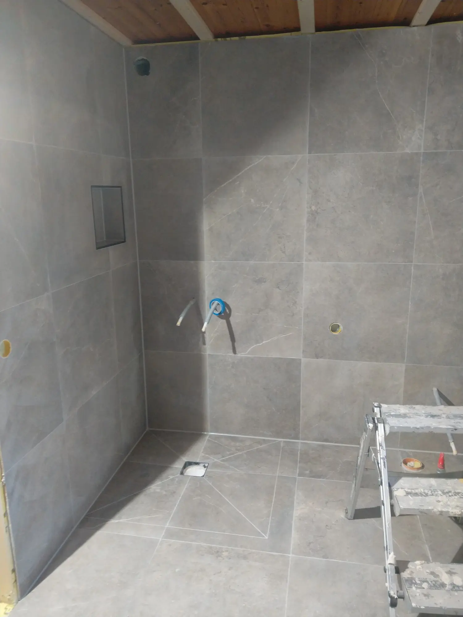 Badrum med väggplattor och golvbrunn.