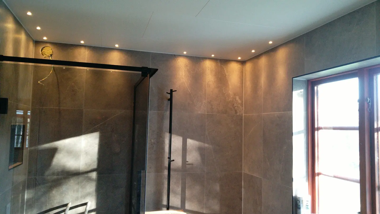 Badrum med stora plattor och dusch.