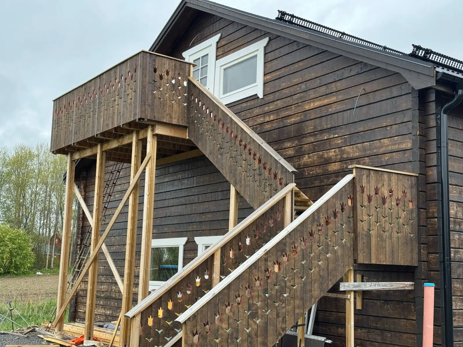 Träbalkong och trappa mot fasad.